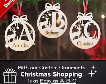 May include: Three wooden Christmas ornaments with a deer and a letter cut out in the center. The ornaments are personalized with the names Annika, Bethany, and Christina.