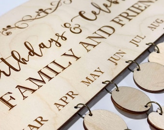May include: A wooden birthday calendar with engraved text reading "Birthdays & Celebrations FAMILY AND FRIENDS." The calendar includes months and small wooden tags for recording birthdays. The design is a light brown color.