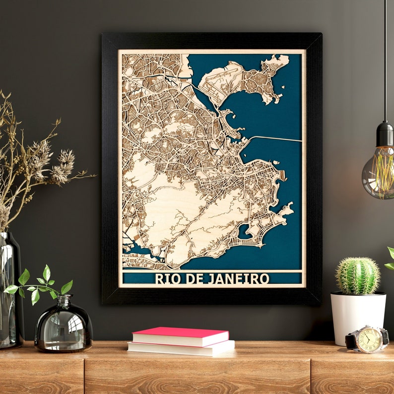 May include: A framed wooden map of Rio de Janeiro, Brazil, showing a detailed street layout and coastline. The map is set against a teal background and framed in black. The city name is displayed in white at the bottom.