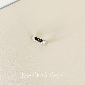 May include: A silver ring with a small gold accent.