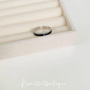 Pu&ograve; includere: Un anello d'argento con una fascia nera attorno al centro.