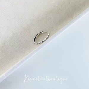 May include: A silver ring with a delicate design and the words "Love You" engraved on the band.