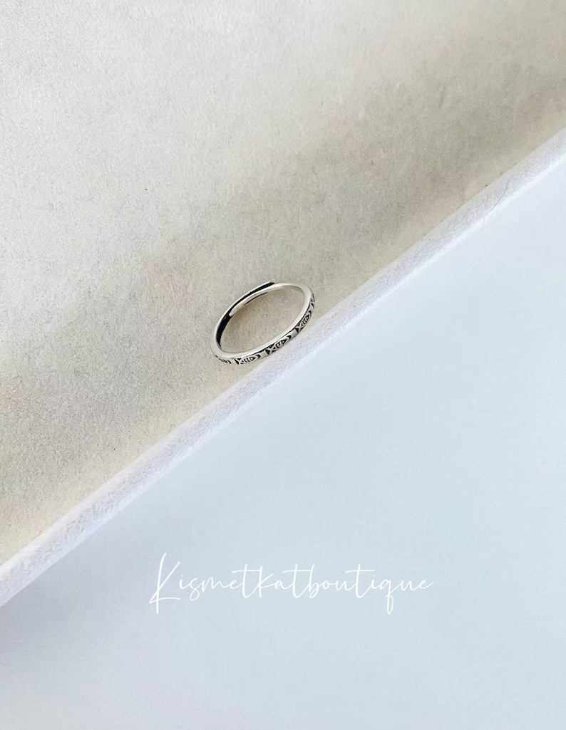 May include: A silver ring with a delicate design and the words "Love You" engraved on the band.