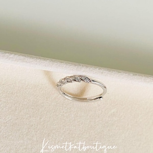 Op de afbeelding: Een verstelbare zilverkleurige ring met een rij kleine, heldere stenen. De ring wordt getoond op een neutrale achtergrond. De tekst "Kismetkatboutique" is zichtbaar in de afbeelding.