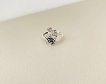 Könnte beinhalten: Ein silberner Ring mit einem zarten Rosenmotiv. Die Rose ist mit filigranen Schnitzereien verziert und auf einem dünnen Band befestigt.
