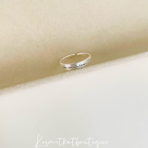 Puede incluir: Un anillo de plata con la palabra "inshallah" inscrita en él.