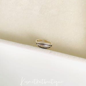 May include: Silver adjustable ring with a detailed fish design.