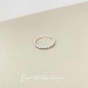 Könnte beinhalten: Ein silberner Zehenring mit einem zarten, filigranen Design. Der Ring ist mit "925" gekennzeichnet, was bedeutet, dass er aus Sterlingsilber besteht.