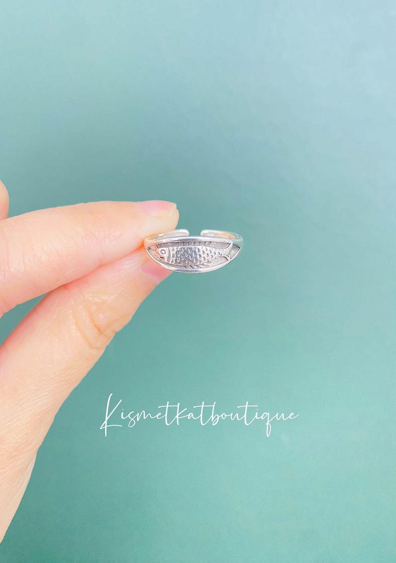 May include: A silver toe ring with a fish design. The ring is adjustable and can be worn on any toe.