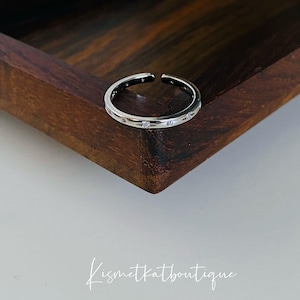 May include: A silver ring with small clear stones set around the band.