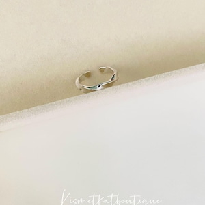 May include: A silver ring with a wavy, textured design.
