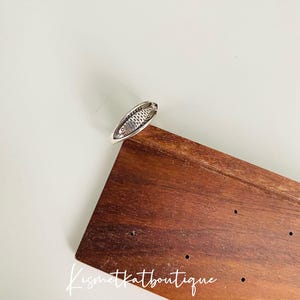 May include: Silver ring with a detailed fish design. The ring is on a wooden surface with the text "Kismetkatboutique" visible.