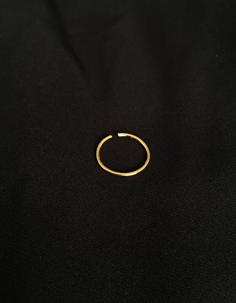 May include: A simple gold ring, a minimalist jewelry piece.