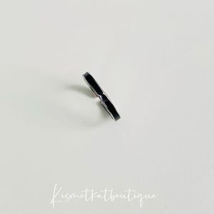Pu&ograve; includere: Un anello nero sottile con una fascia argentata.
