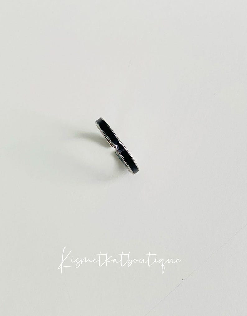 Pu&ograve; includere: Un anello nero sottile con una fascia argentata.