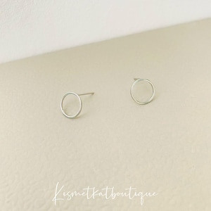 May include: A pair of silver circle stud earrings. The earrings are simple and minimalist.