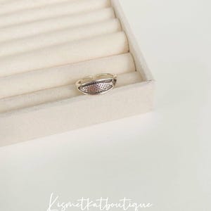May include: A silver adjustable ring with a fish design. The ring is on a white background.