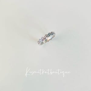 Op de afbeelding: Zilveren ring met een golvende, getextureerde band.
