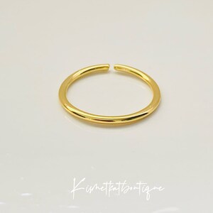 May include: A simple gold ring with a smooth, rounded surface.