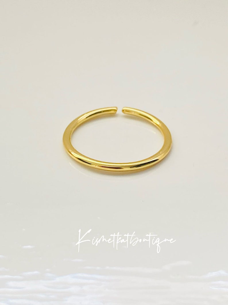 May include: A simple gold ring with a smooth, rounded surface.
