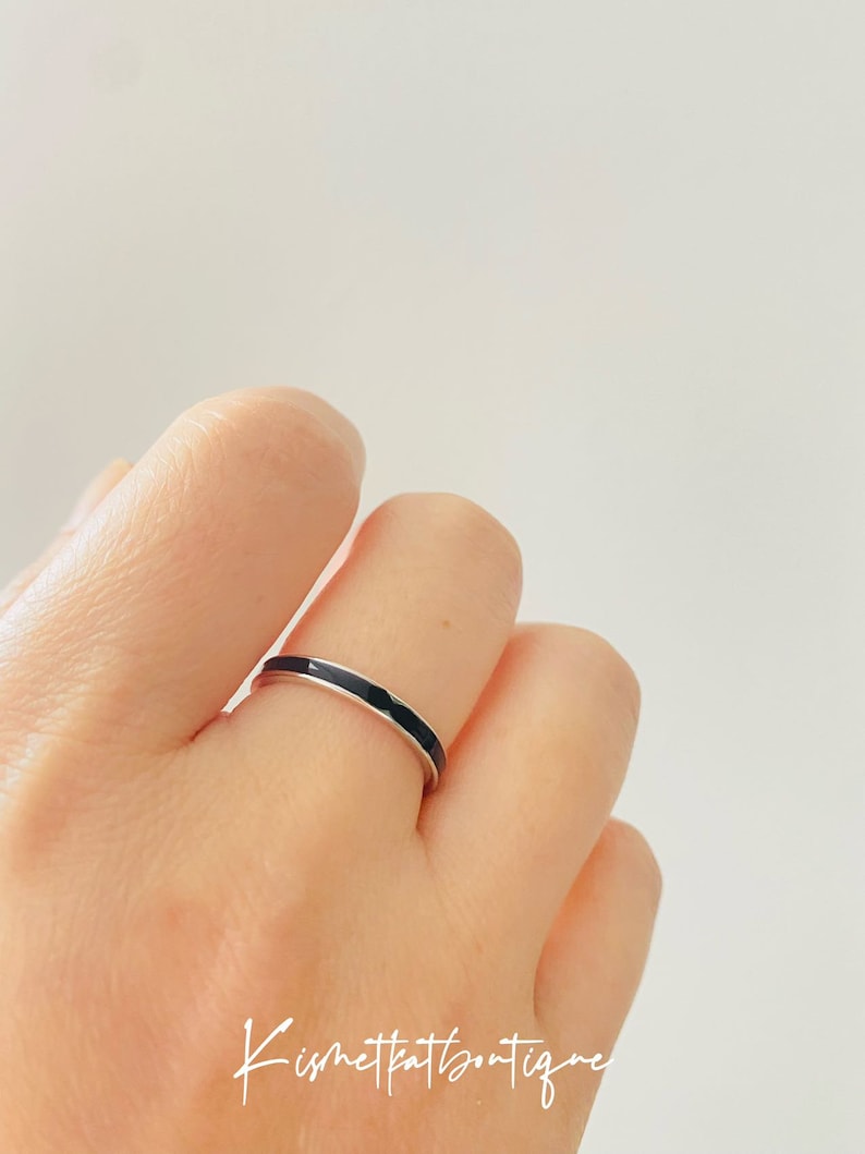 Pu&ograve; includere: Un sottile anello a fascia d'argento con una striscia di smalto nero.