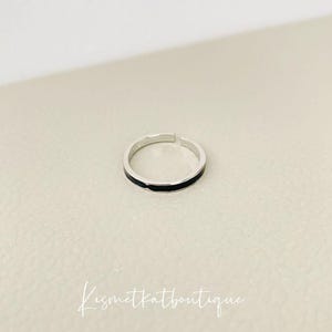 Pu&ograve; includere: Un anello d'argento con una sottile fascia nera attorno al centro.