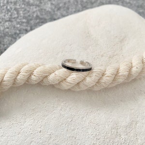 Pu&ograve; includere: Un anello d'argento con una fascia nera attorno al centro.