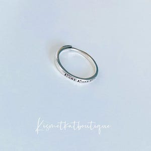 May include: A silver ring with a delicate design. The ring is simple and elegant, perfect for everyday wear.