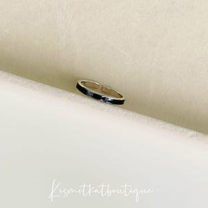Pu&ograve; includere: Un anello d'argento con una fascia in smalto nero. L'anello &egrave; aperto e regolabile.