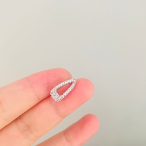 May include: A small, silver, teardrop-shaped earring with a clear crystal design.