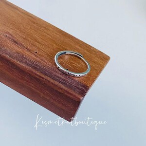 May include: A silver ring with a delicate design on a wooden surface.