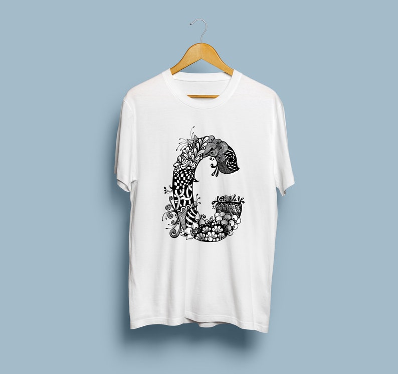 K&ouml;nnte beinhalten: Wei&szlig;es T-Shirt mit einem schwarzen und wei&szlig;en Doodle-Design des Buchstabens C.