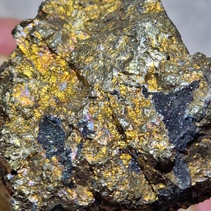 May include: A rough, irregularly shaped piece of pyrite with a metallic gold and black colour. The pyrite has a rough, textured surface and a slightly iridescent sheen.
