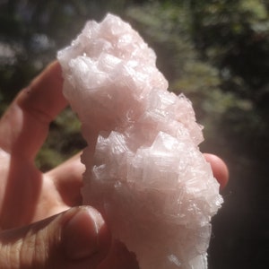 May include: A large, pink Himalayan salt crystal with a rough, textured surface.