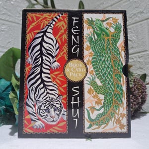 May include: A rectangular book and card pack box featuring a white tiger with black stripes on a red background with gold bamboo patterns on the left, and a green dragon on a white background with gold leaf patterns on the right, with the text Feng Shui.