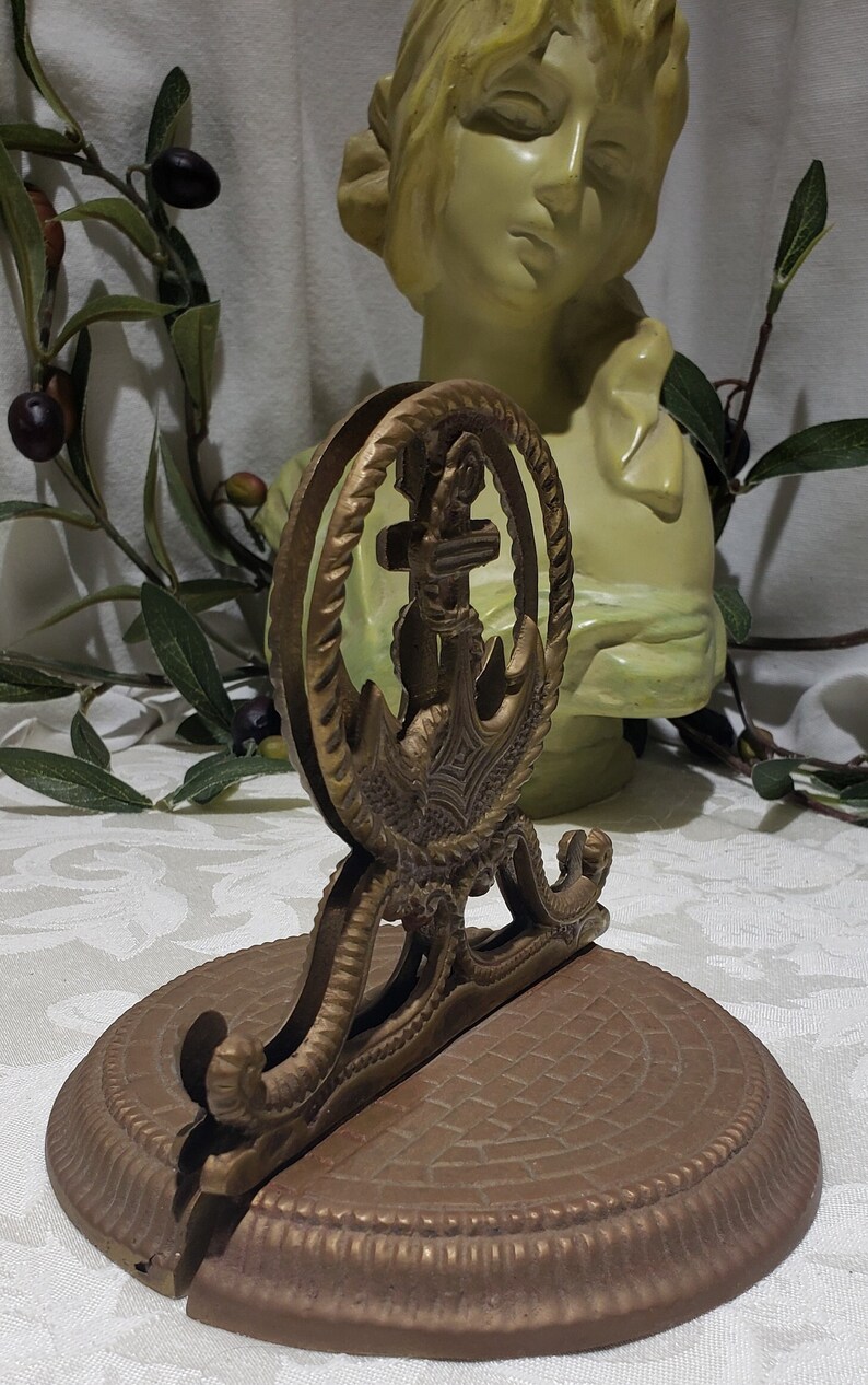 May include: A brass napkin holder with an anchor design. The holder has a round base and a decorative top with a rope design.