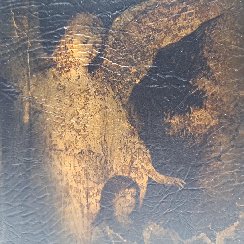 May include: An antique painting with a dark, textured background. The artwork features a figure with a golden-brown hue, possibly an angel or a religious figure, and a person in the foreground. The painting has a distressed, aged appearance.