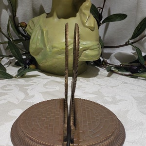 May include: A pair of antique brass bookends with a decorative design. The bookends have a circular base with a textured pattern and a decorative top with a floral design.