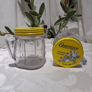 May include: A yellow and clear plastic Osterizer mini-blend container with a lid. The lid has a chef illustration and the text "Osterizer Liquefier-Blender Mini-Blend Container Blend and Store".
