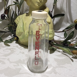 May include: A clear glass baby bottle with a white plastic lid and red lettering that reads "Evenflo" and "Made in USA".