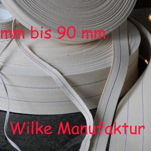 May include: Off-white woven elastic band rolls with blue stitching. The text on the image reads "4.5 mm bis 90 mm" and "Wilke Manufaktur".