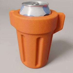May include: A bright orange, textured beverage cooler shaped like a flower pot with vertical indentations along the sides. A silver aluminum drink can with blue and white circular patterns is inserted into the top opening of the cooler.