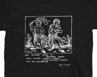 May include: Black t-shirt featuring a white illustration of two figures holding whips. The text reads "your incredible ability to thoroughly imagine every possible negative outcome of any particular situation feels like self-mastery but it isn't."