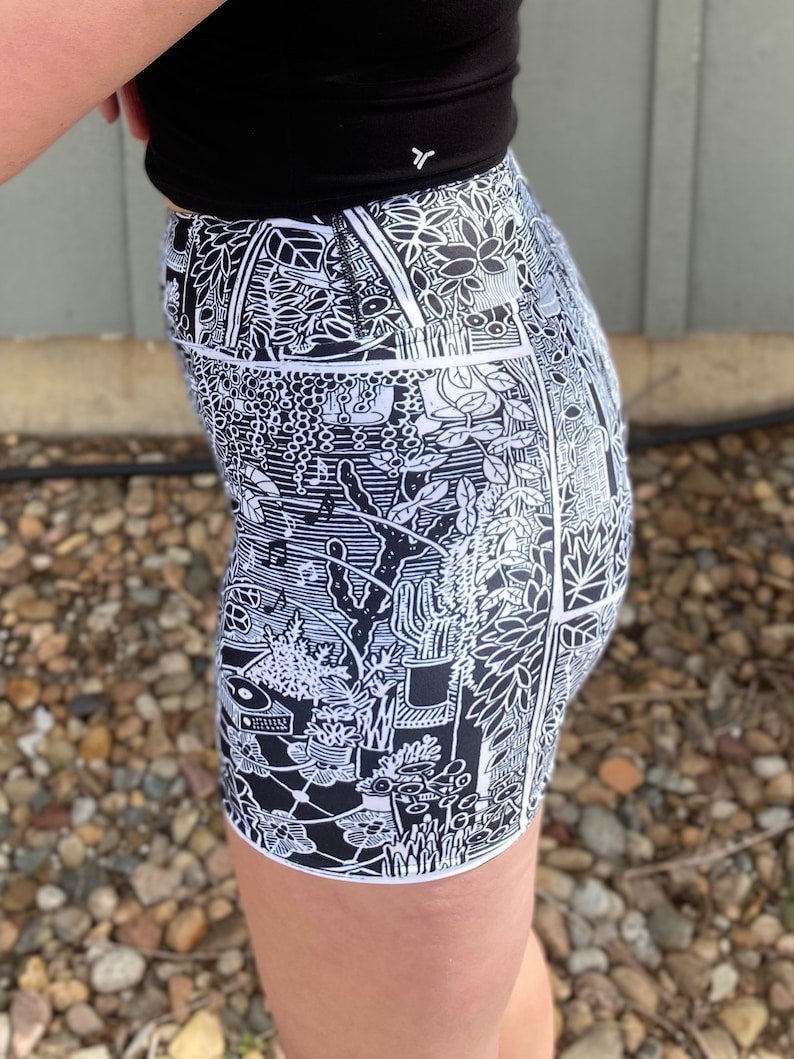 May include: Black and white patterned shorts with a botanical design. The shorts are made of a stretchy fabric and have a high waist.