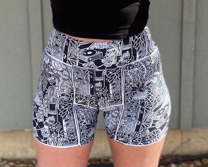 May include: Black and white patterned athletic shorts with a high waist and a graphic print of plants, furniture, and other objects.