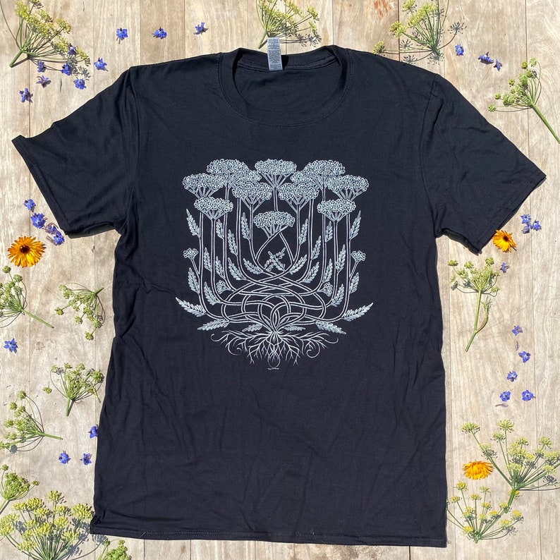 K&ouml;nnte beinhalten: Ein schwarzes T-Shirt mit einer wei&szlig;en Grafik eines stilisierten B&uuml;schels Schafgarbenbl&uuml;ten.