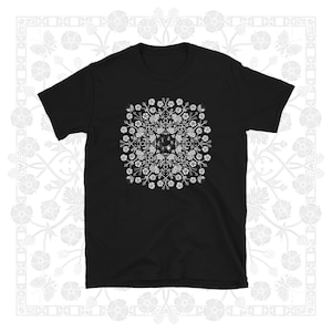 May include: Black t-shirt with a white floral pattern in the center. The pattern is a symmetrical design with a circular shape.