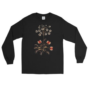 May include: Black long-sleeve t-shirt with a graphic print of a carnivorous plant with white flowers. The plant has red, orange, and green details.