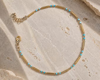 Può includere: Un delicato bracciale a catena color oro caratterizzato dall'alternanza di piccole perline color turchese e perline tubolari cilindriche allungate color oro. Il bracciale include una chiusura a moschettone e una catenella di estensione regolabile.
