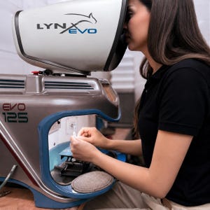 Pu&ograve; includere: Un microscopio stereo Lynx Evo 125 con un alloggiamento bianco e grigio metallizzato. Il dispositivo presenta una grande cappa di visione, un bordo blu attorno all'area di lavoro centrale e la scritta LYNX EVO ed EVO 125 sull'esterno.